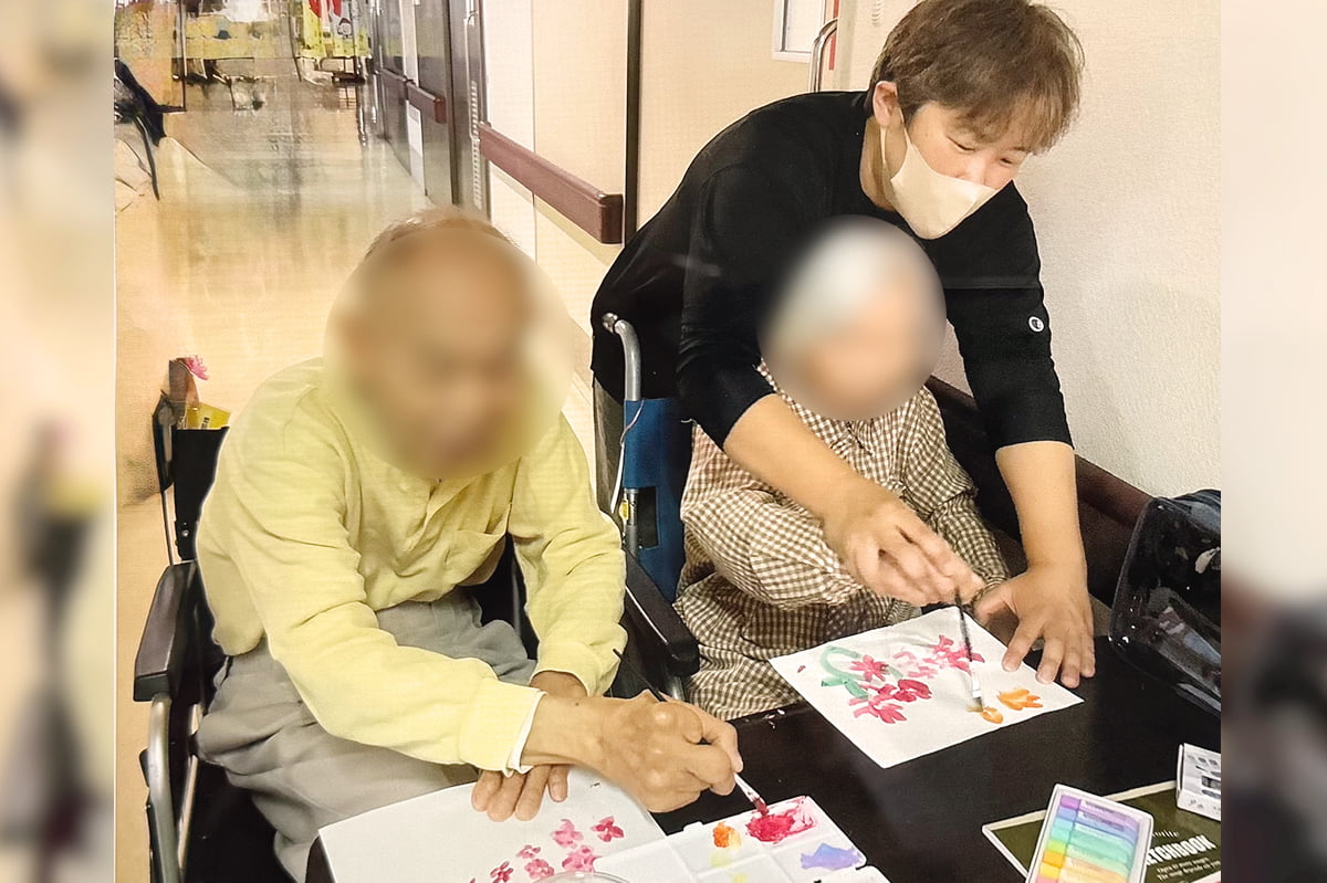 入居者と塗り絵をするアイちゃん